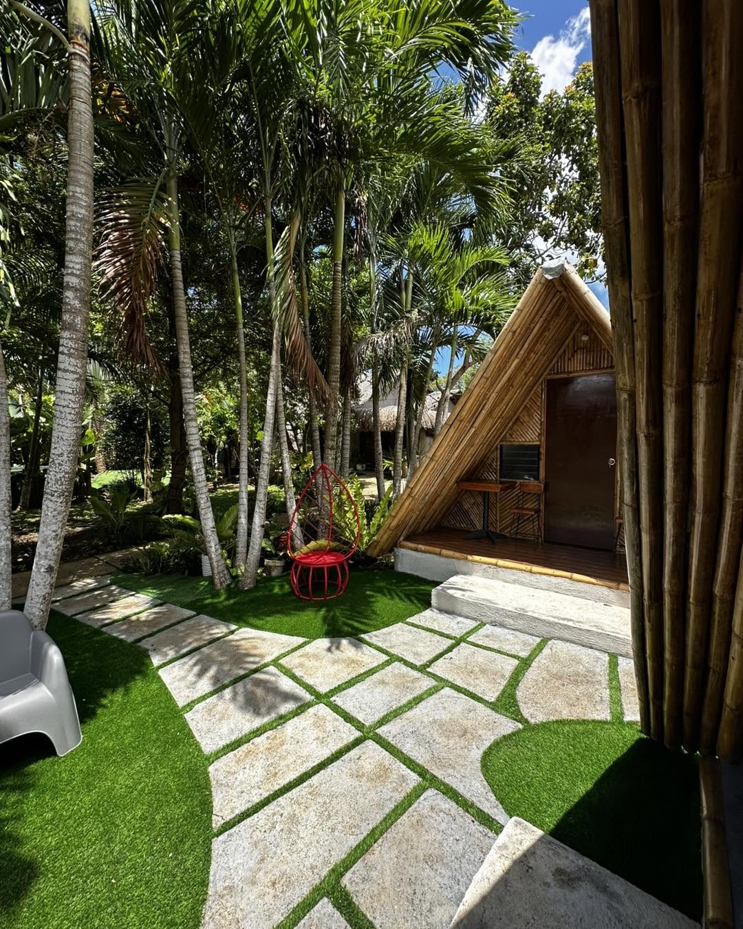 A-frame cottage with a red accent chair beside a stone garden path