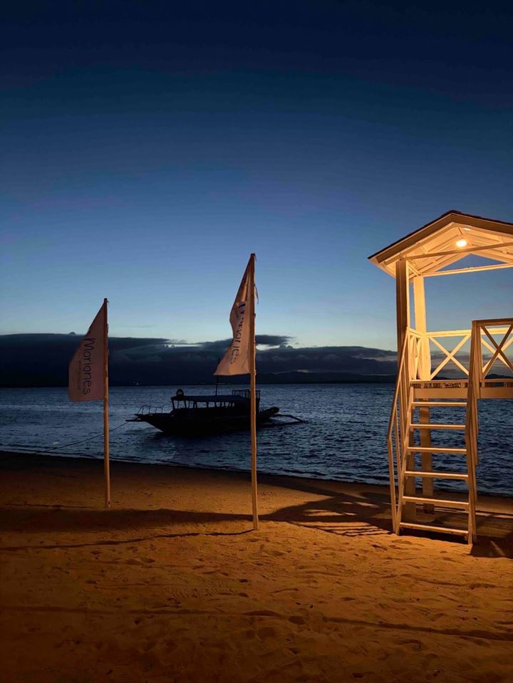 The beach at blue hour with a lit lookout tower and resort flags