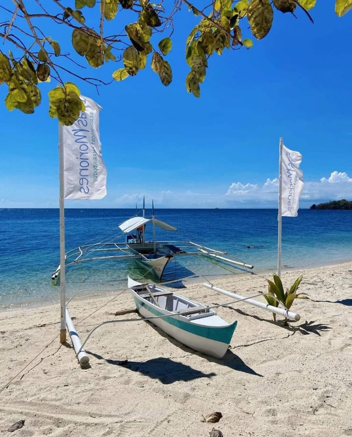 Outrigger boats on the resort's beach between two resort flags