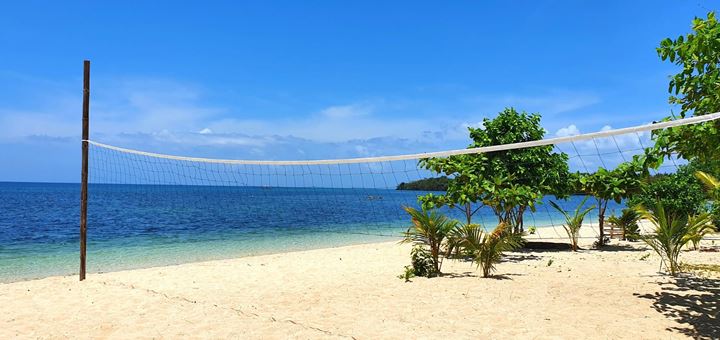 A volleyball net on pale sand at the water's edge
