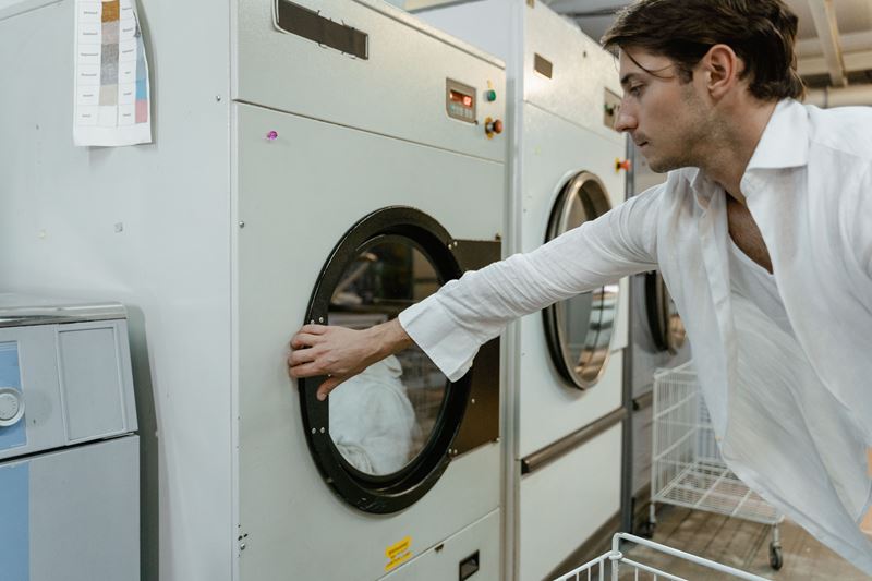 A man loading white linen into a front-loading machine