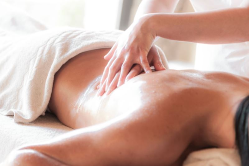 Hands giving a relaxing back massage to a guest lying under a white towel