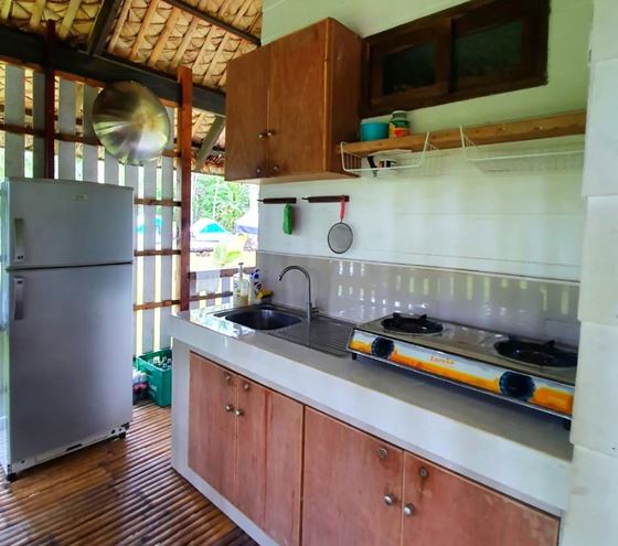 A timber-built kitchen with a two-burner stove, sink and refrigerator