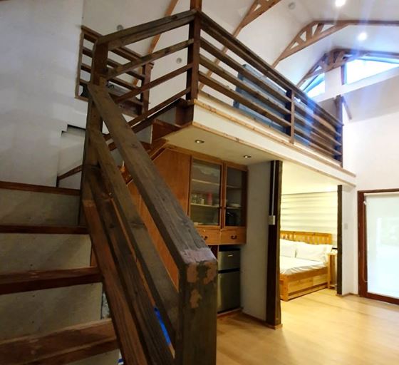 Timber stairs to the Kubo loft beside glass-fronted cabinets and a small refrigerator