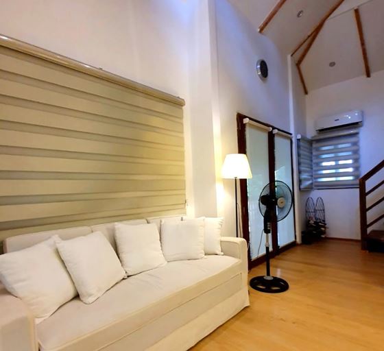 A white couch under the high timber-beamed ceiling of the Luxury Kubo