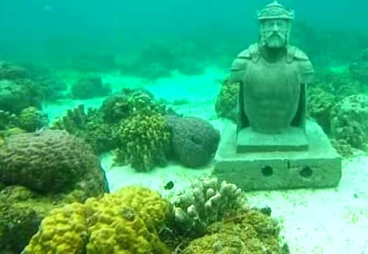 An underwater Morion statue among coral