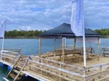 A floating bamboo raft with a dark canopy on calm water