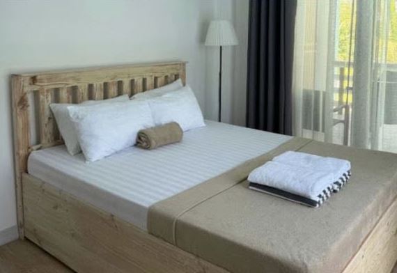 Deluxe Room: a queen bed with a slatted timber headboard and a glass door to a balcony