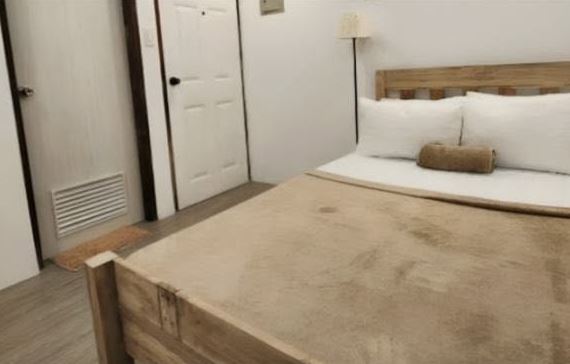 Double Standard Room: a timber-framed bed with white pillows and a soft throw