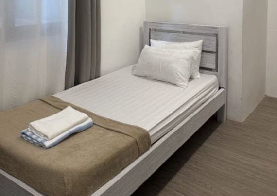 Single Standard Room: a single bed with white linen and folded towels beside a curtained window