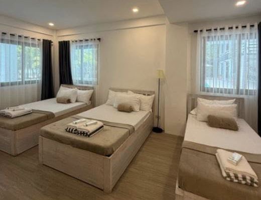 Suite Room: two twin beds and a single bed under bright windows