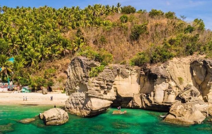 Limestone rocks and arches of Ungab Rock Formation around a green cove