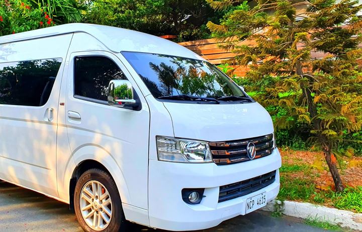 The resort's white Foton high-roof van parked on a tree-lined street