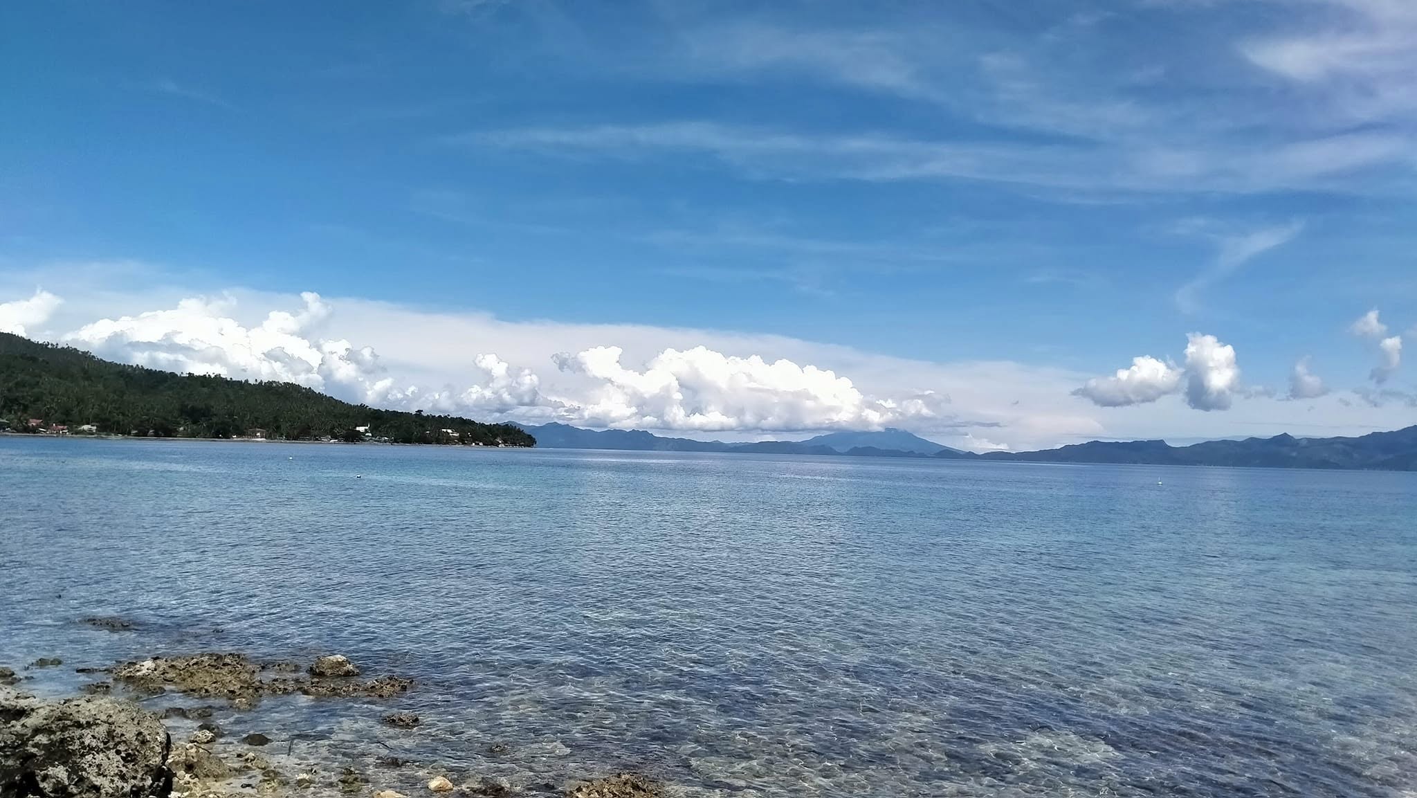 Wide panoramic view across calm Sogod Bay under a bright blue sky