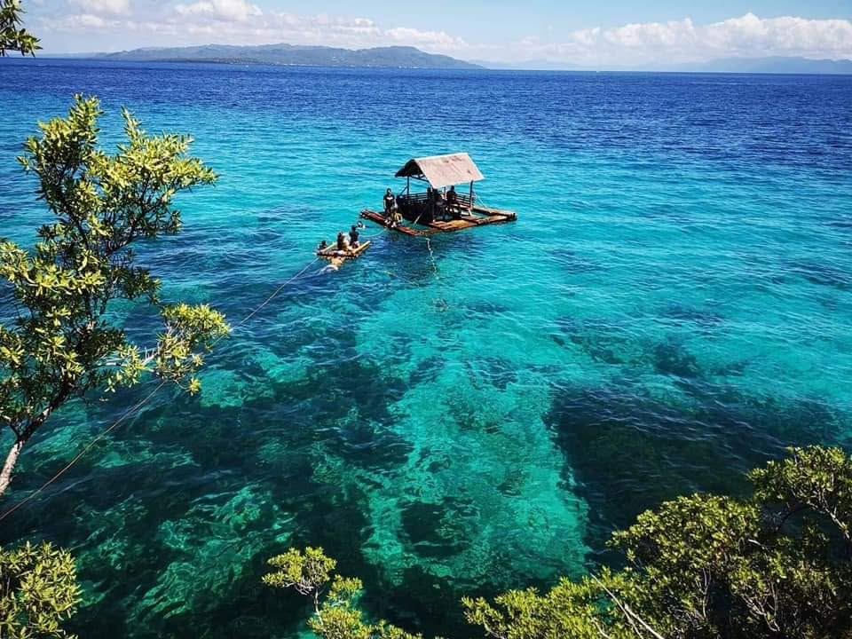 A floating bamboo cottage over clear turquoise water near Padre Burgos