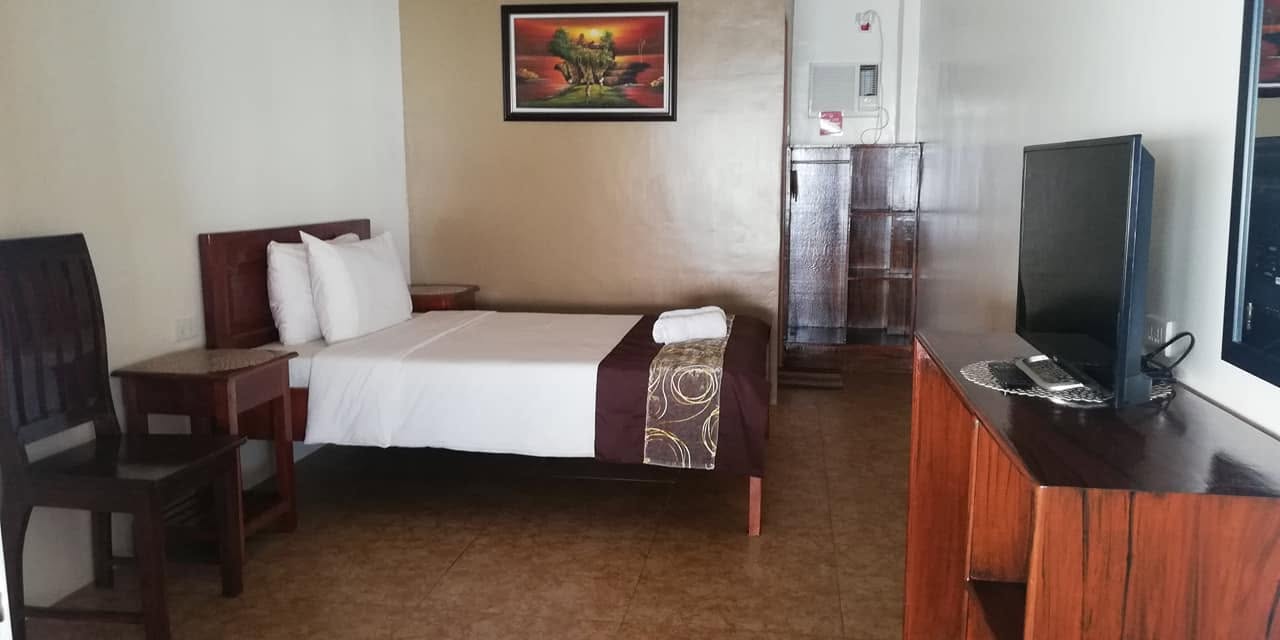 A single-bed guest room with air conditioning and TV