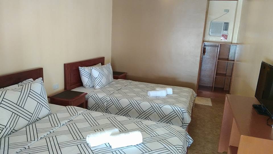 A twin-bed guest room at JD Beach Front Hotel with fresh linens, air conditioning and an en-suite bathroom