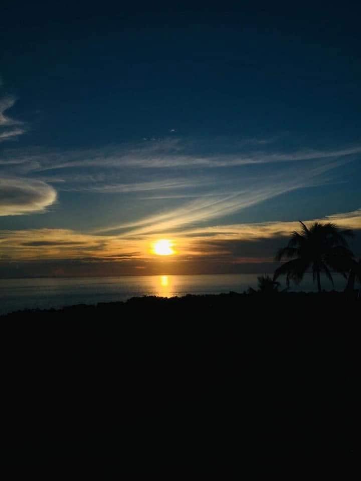 Sunset over the water with silhouetted palm trees near Padre Burgos