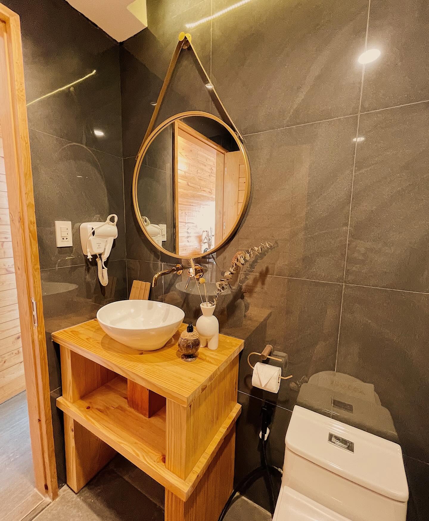 Ensuite with dark stone tile, round mirror and vessel basin