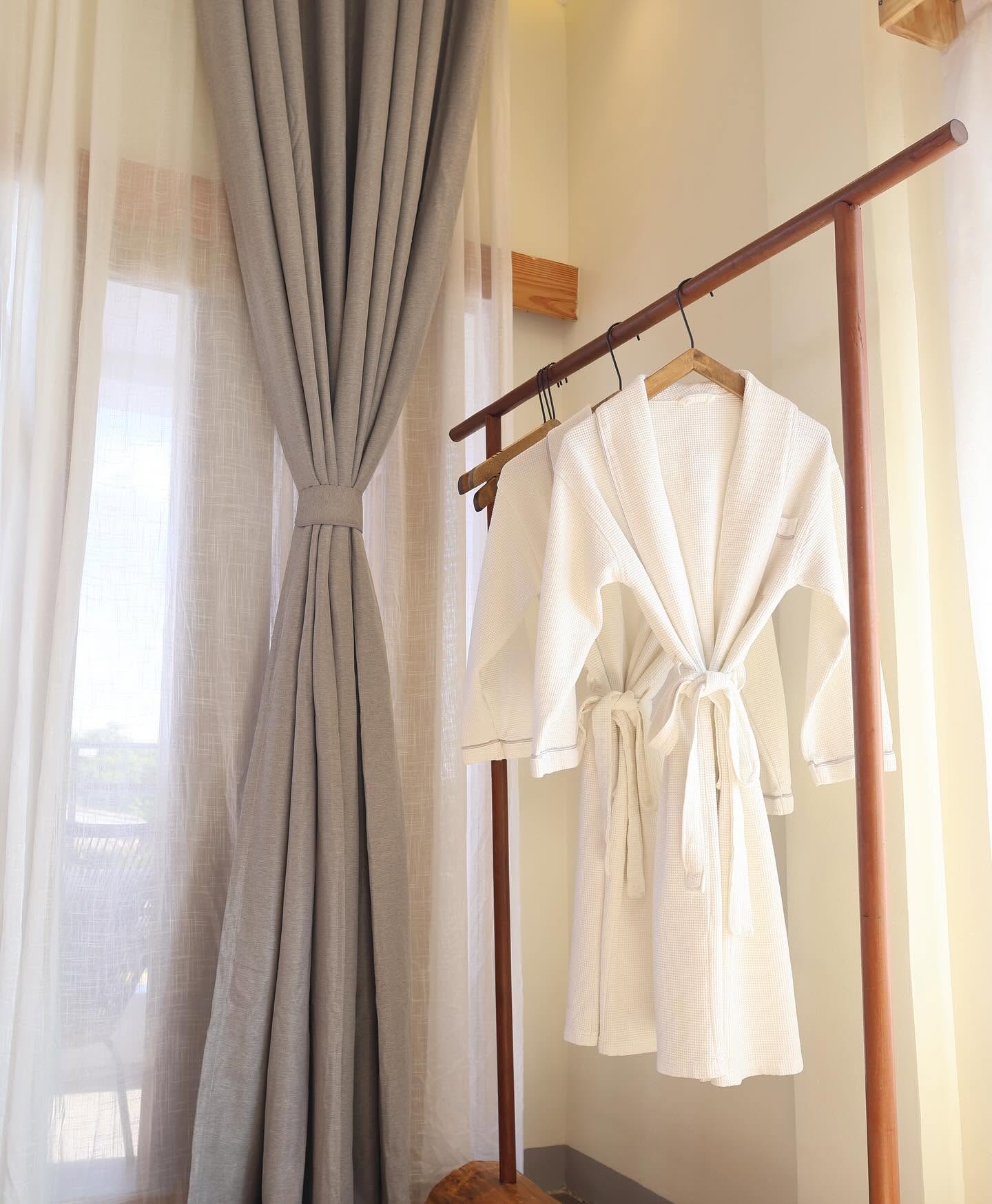 White waffle robes on a timber rack by the window