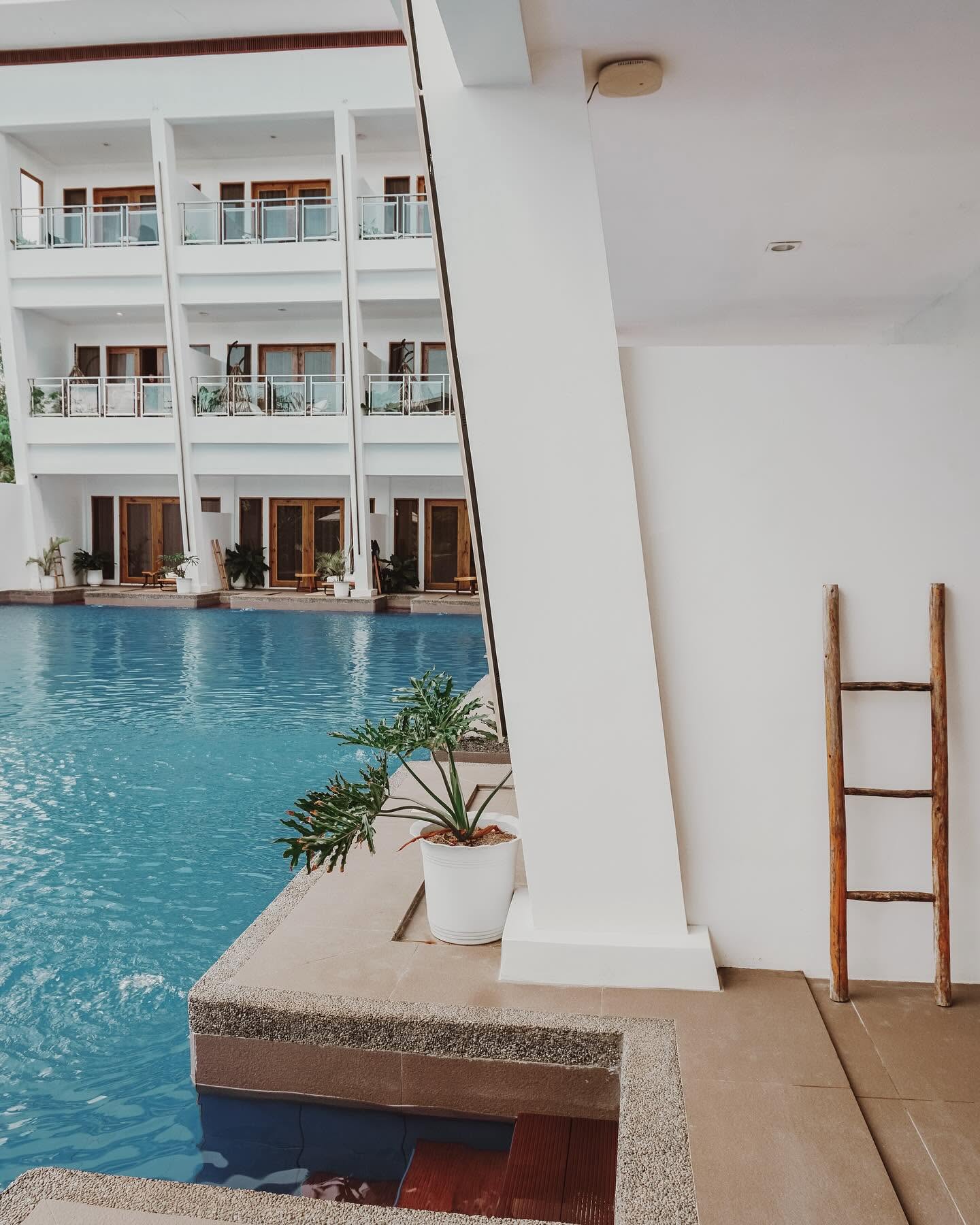 Pool edge with a decorative timber ladder against a white wall