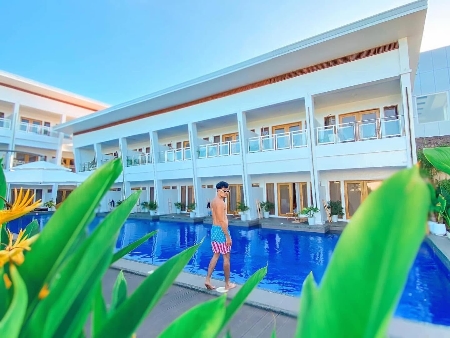 Guest walking the pool edge past the two-storey building