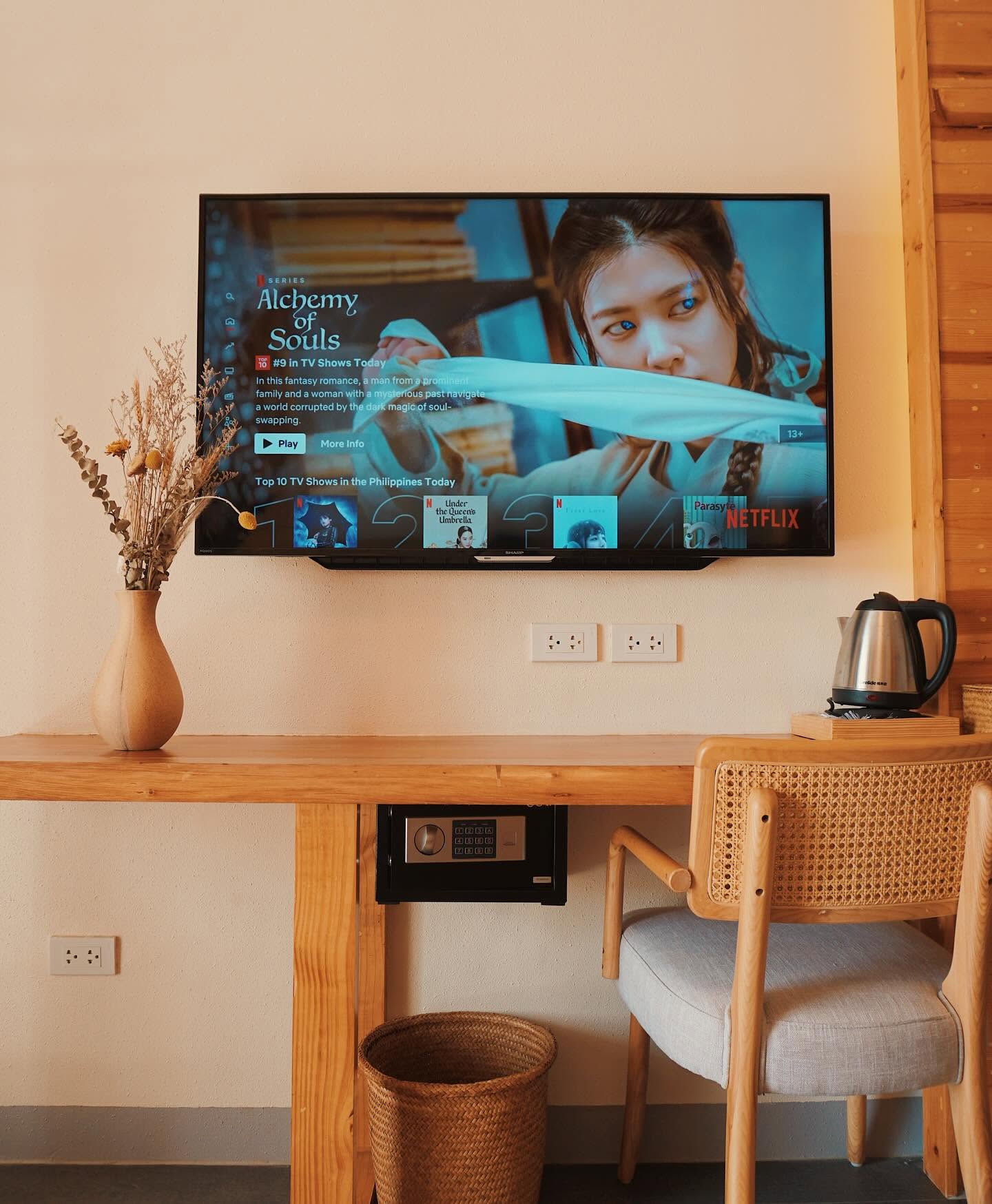 In-room desk with a wall-mounted smart TV and cane chair