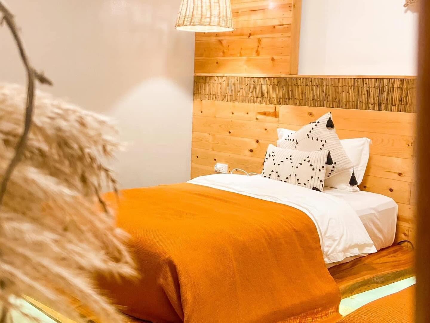 Single bed with a terracotta throw and pampas grass